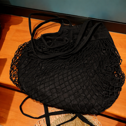 Black mesh bag with a black garment on a wooden surface